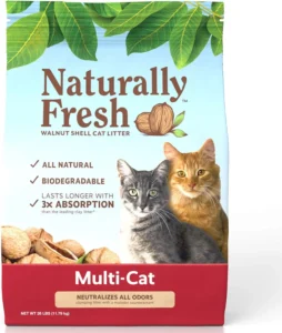 A bag of Naturally Fresh walnut shell cat litter featuring a light blue background with green leaves across the top. The package displays "Naturally Fresh" in large brown lettering with "WALNUT SHELL CAT LITTER" beneath it, accompanied by an illustration of a walnut with small green leaves. Two cats are prominently featured in the center - a gray tabby cat with green eyes on the left and an orange tabby cat with amber eyes on the right. The package lists key features including "ALL NATURAL," "BIODEGRADABLE," and "LASTS LONGER WITH 3X ABSORPTION than the leading clay litter." A red banner at the bottom reads "Multi-Cat" with text stating "NEUTRALIZES ALL ODORS" and noting it's a "clumping litter with a malodor counteractant." Walnut shells are visible in the bottom left corner, and the package indicates a net weight of 26 LBS (11.79 kg).